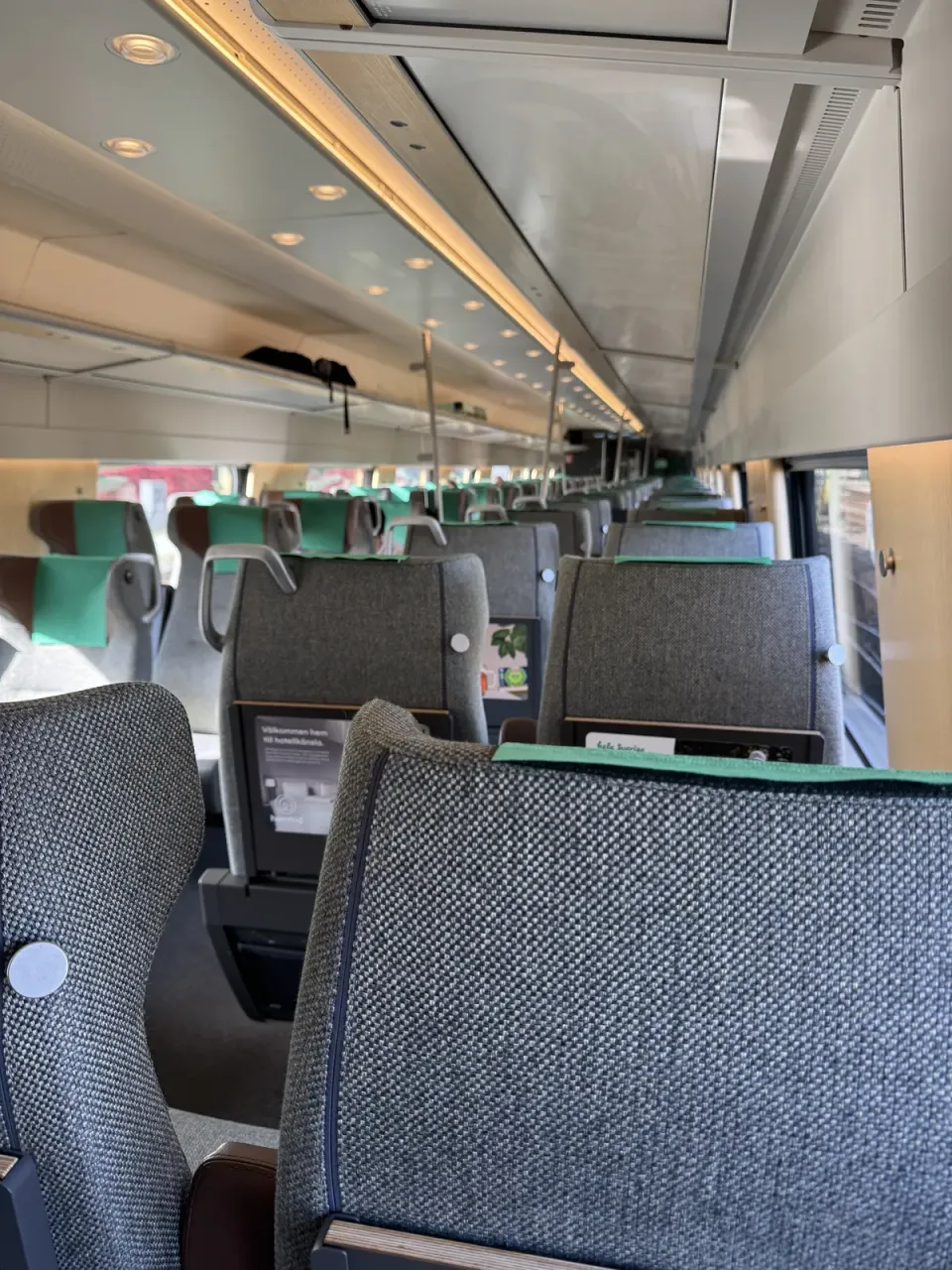 Rangées de sièges et porte-bagages dans une voiture de train lumineuse